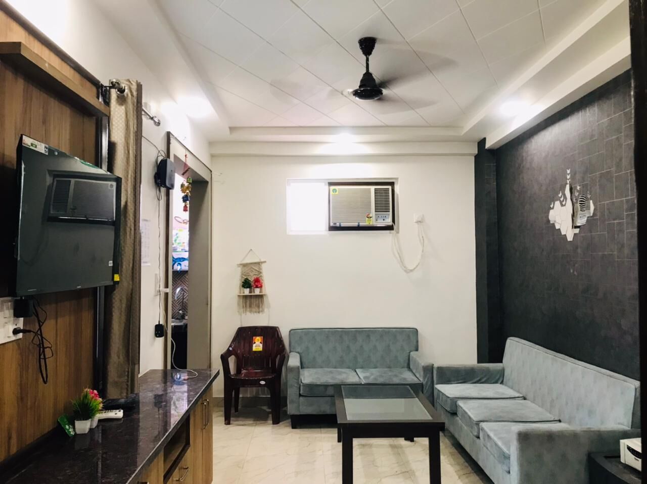 Una sala de estar con sofá, mesa de centro, televisor y aire acondicionado.
