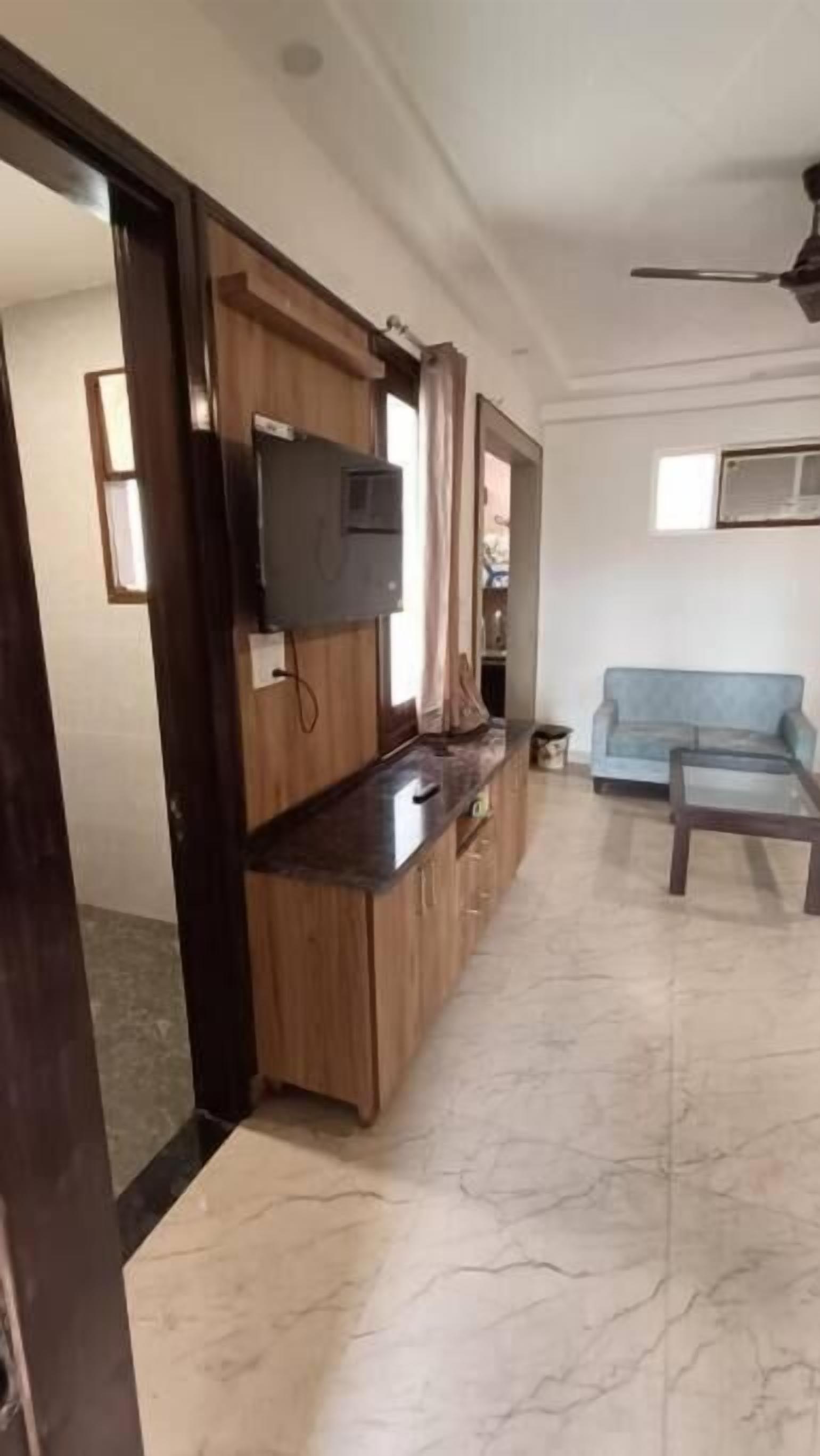 Una sala de estar con televisor, sofá y un mueble de madera.
