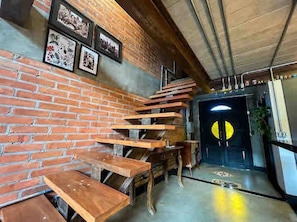 Una escalera de madera que lleva a una puerta con un letrero amarillo circular.