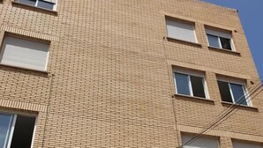 Un immeuble à plusieurs étages, doté d’une façade en briques et de murs blancs.