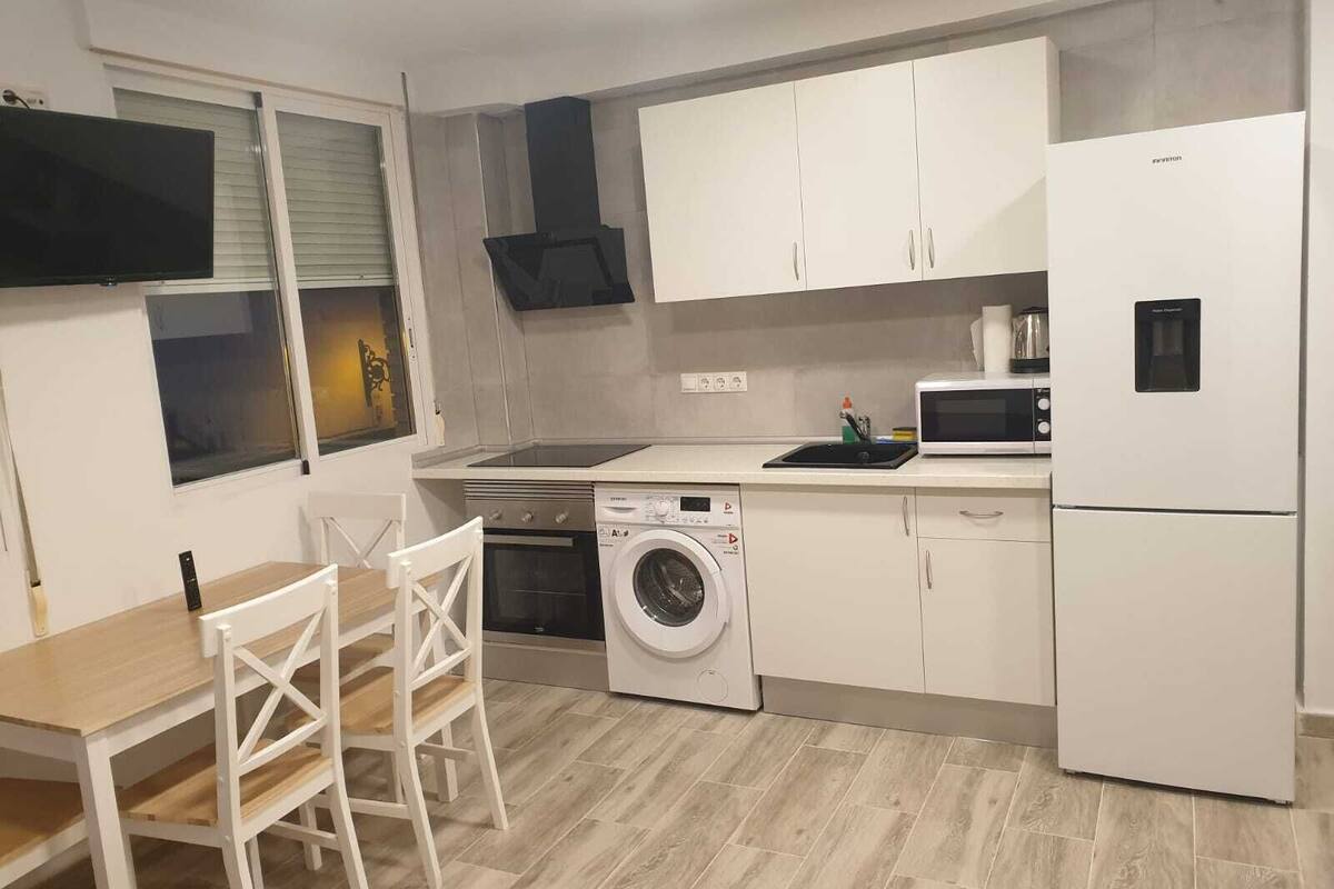 Een moderne keuken met witte kasten, een inbouwoven, een magnetron, een vaatwasser en een koelkast.