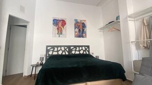 Une chambre à coucher comprenant un lit, un canapé, un luminaire suspendu et deux tableaux accrochés au mur.