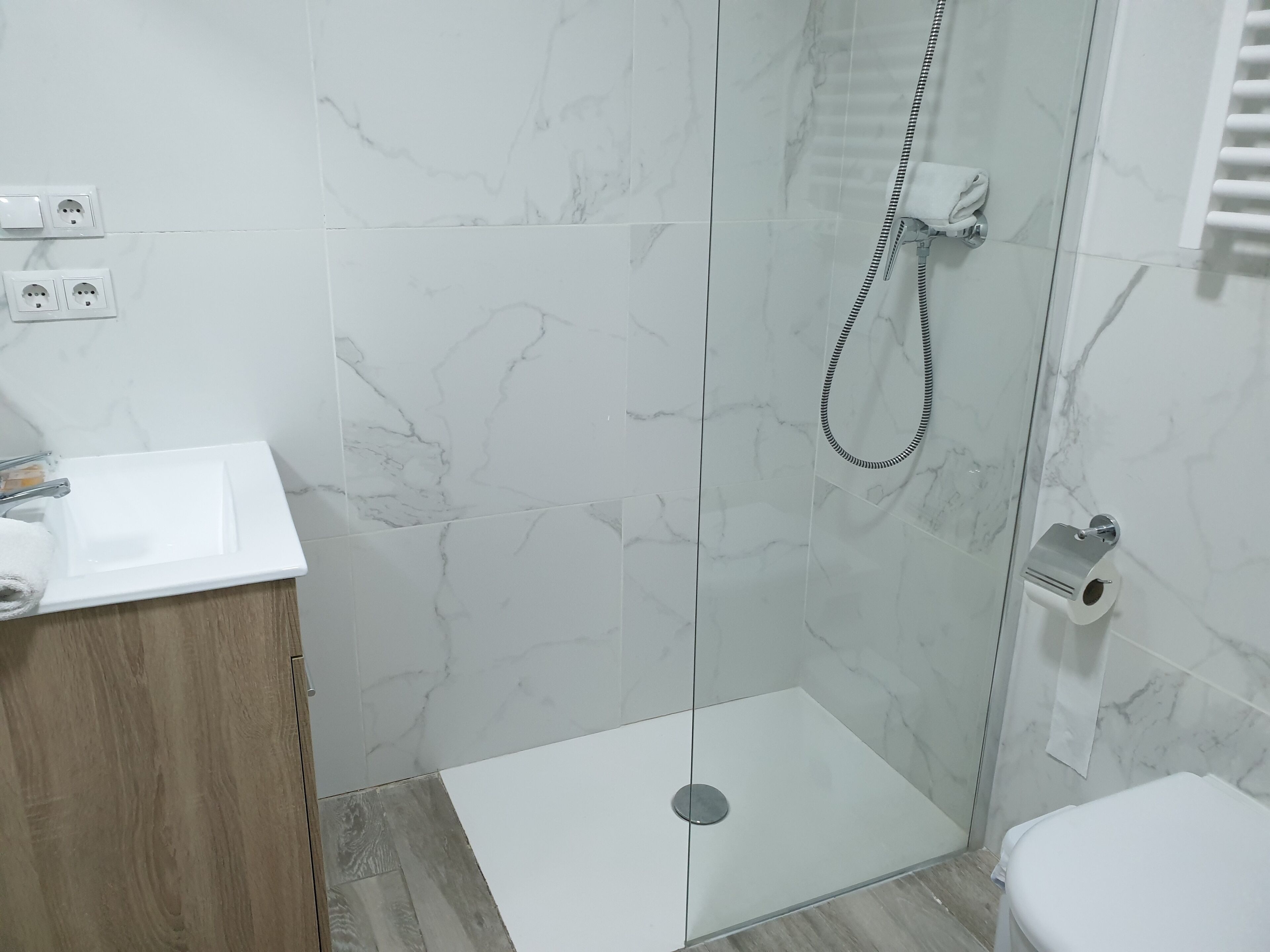 Un baño moderno con cabina de ducha de vidrio, lavamanos blanco y un inodoro.
