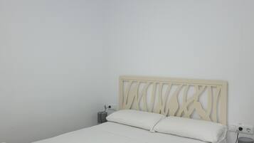 A bedroom with a bed, a nightstand, a lamp, a ceiling fan, and a power outlet.