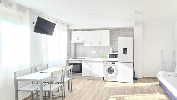 Une cuisine compacte comprenant un coin repas, un lave-linge et un réfrigérateur.