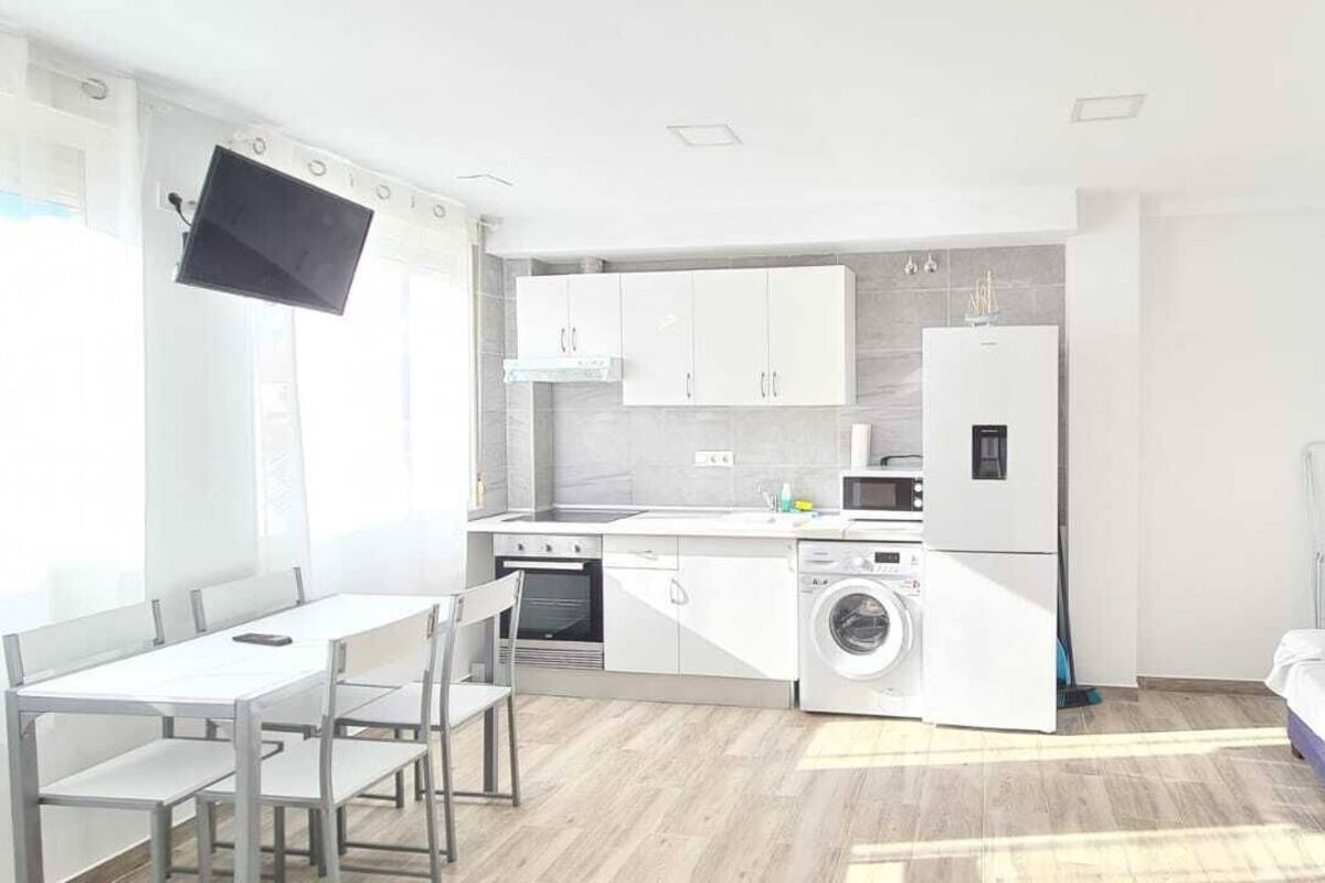 Een kleine keuken met een eethoek, een wasmachine en een koelkast.