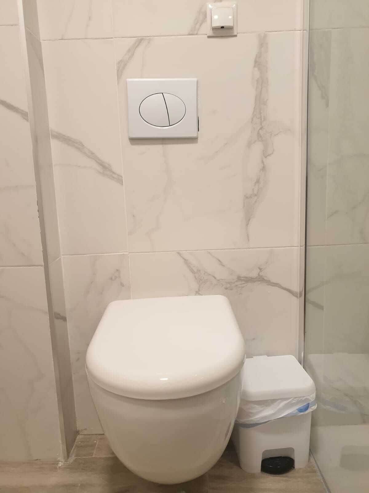 A bathroom with a toilet and a trash bin.