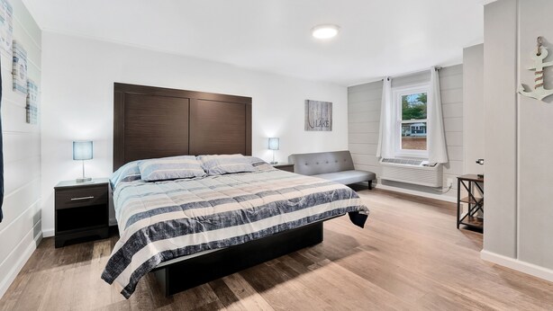 A bedroom with a large bed, bedside tables, a grey sofa, and a window with curtains.