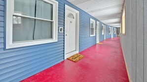 A hallway with blue siding, white trim, and a red floor.