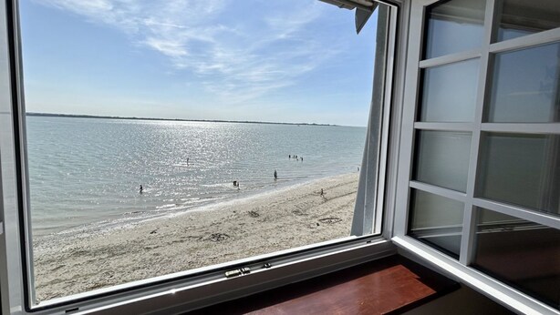 A view through a window of a beach with a clear sky.