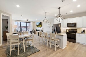 A modern kitchen with white cabinets, a central island, and stainless steel appliances. - NEW Topsider Condominium: MM 19 Arcade game, shuffleboard table (Osage Beach)