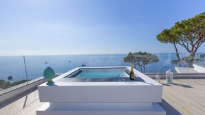 Un bain à remous extérieur moderne offrant une vue dégagée sur la mer et les bateaux.