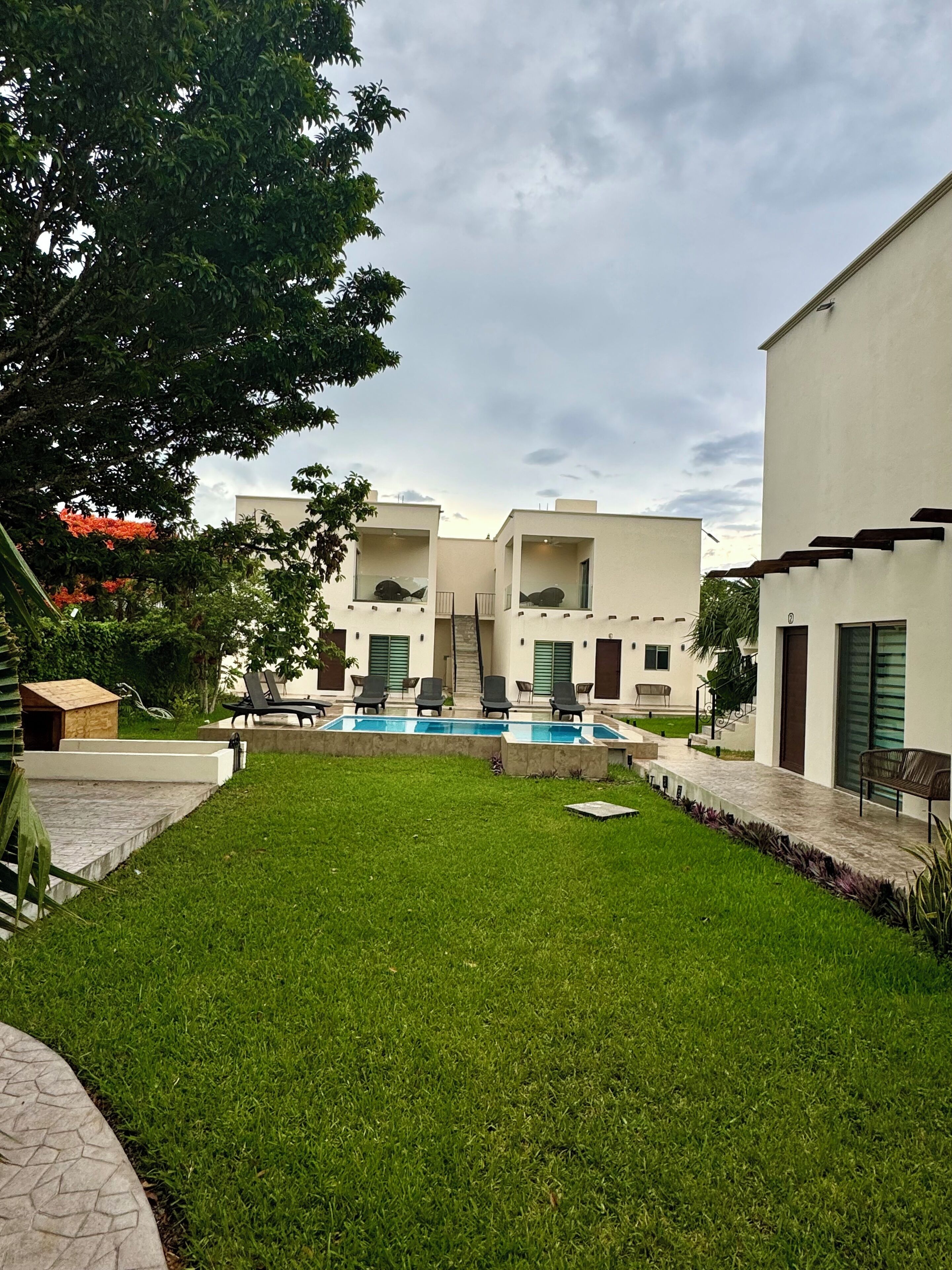 A modern building with a swimming pool, green lawn, and outdoor seating area.