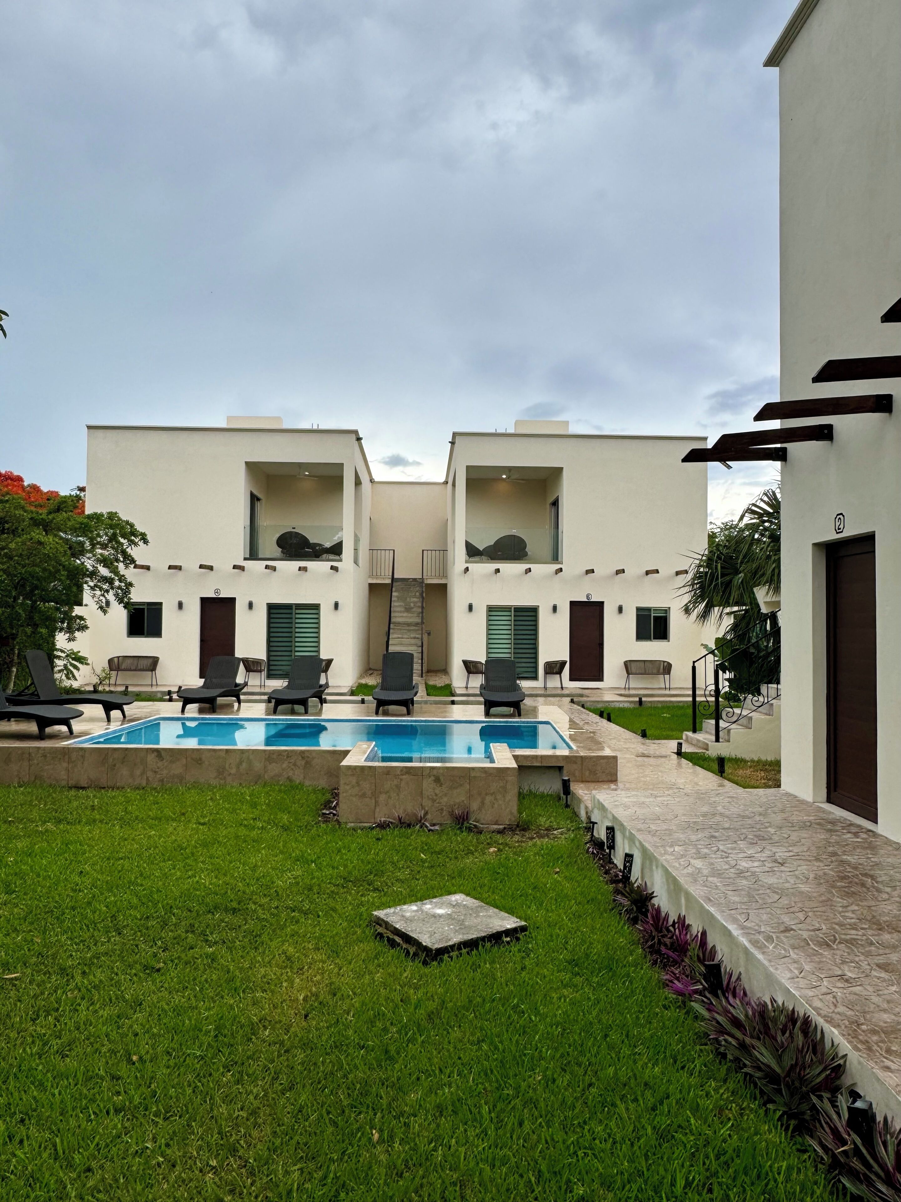 A modern building with a swimming pool, outdoor seating, and a well-maintained lawn.