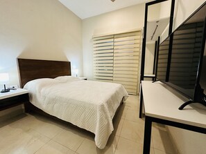 A bedroom with a bed, bedside table, lamp, and a large mirror.