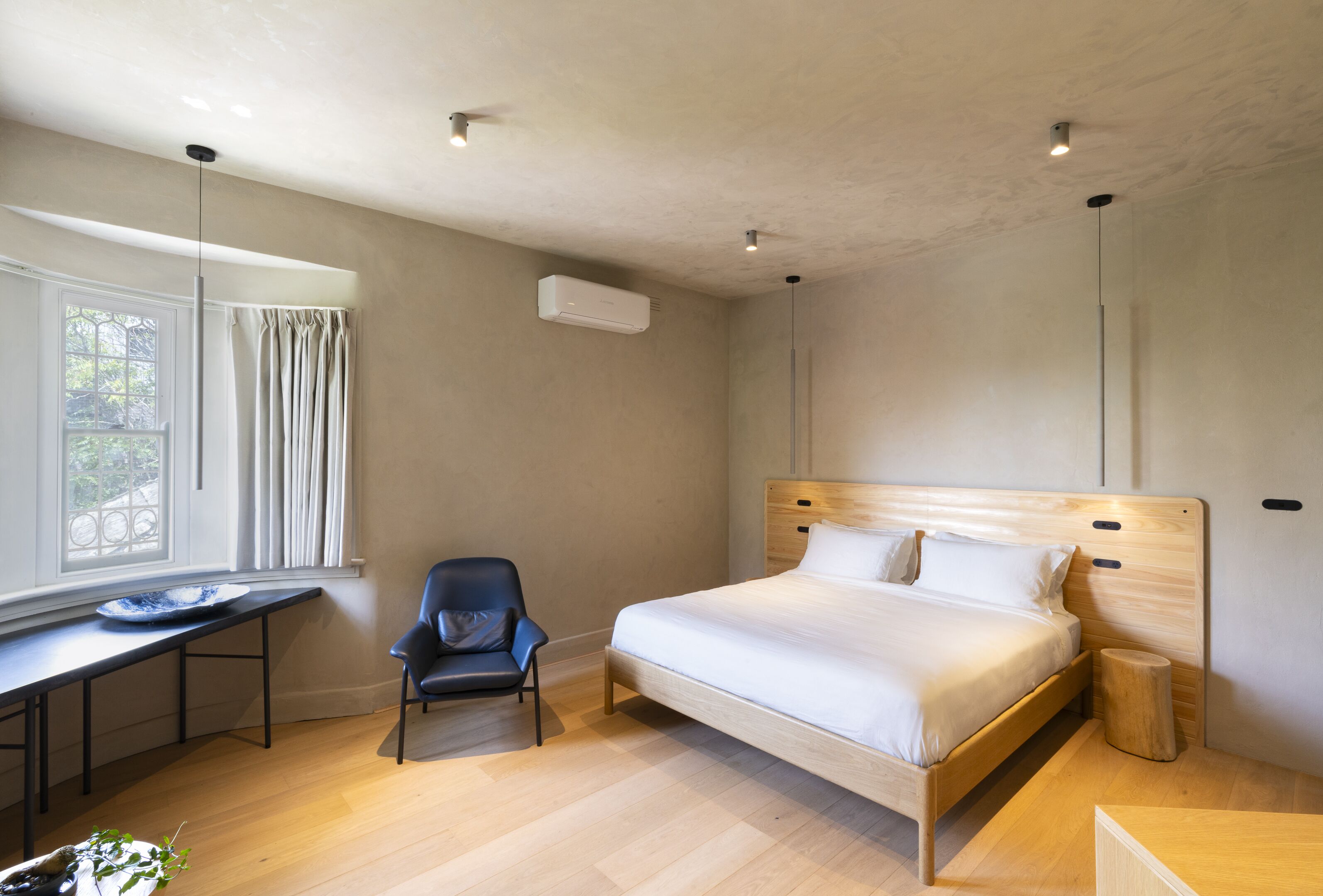 Une chambre à coucher comprenant un lit, un bureau, une chaise, une table de chevet et une fenêtre avec des rideaux.