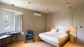 Une chambre à coucher comprenant un lit, un bureau, une chaise, une table de chevet et une fenêtre avec des rideaux.