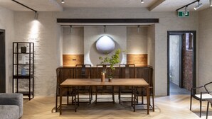 Un espace repas moderne avec une longue table en bois, six chaises et un vase central agrémenté de plantes.