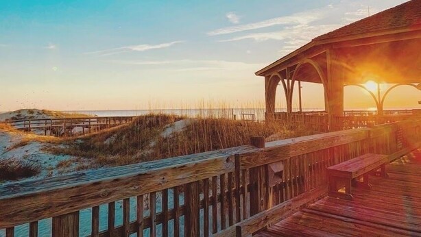 A wooden pier leading to a covered area with a sunset in the background. - Great Summer Rates 1B 1B South beach-Steps to pool-beach-restaurants-nightlife! (Tybee Island)