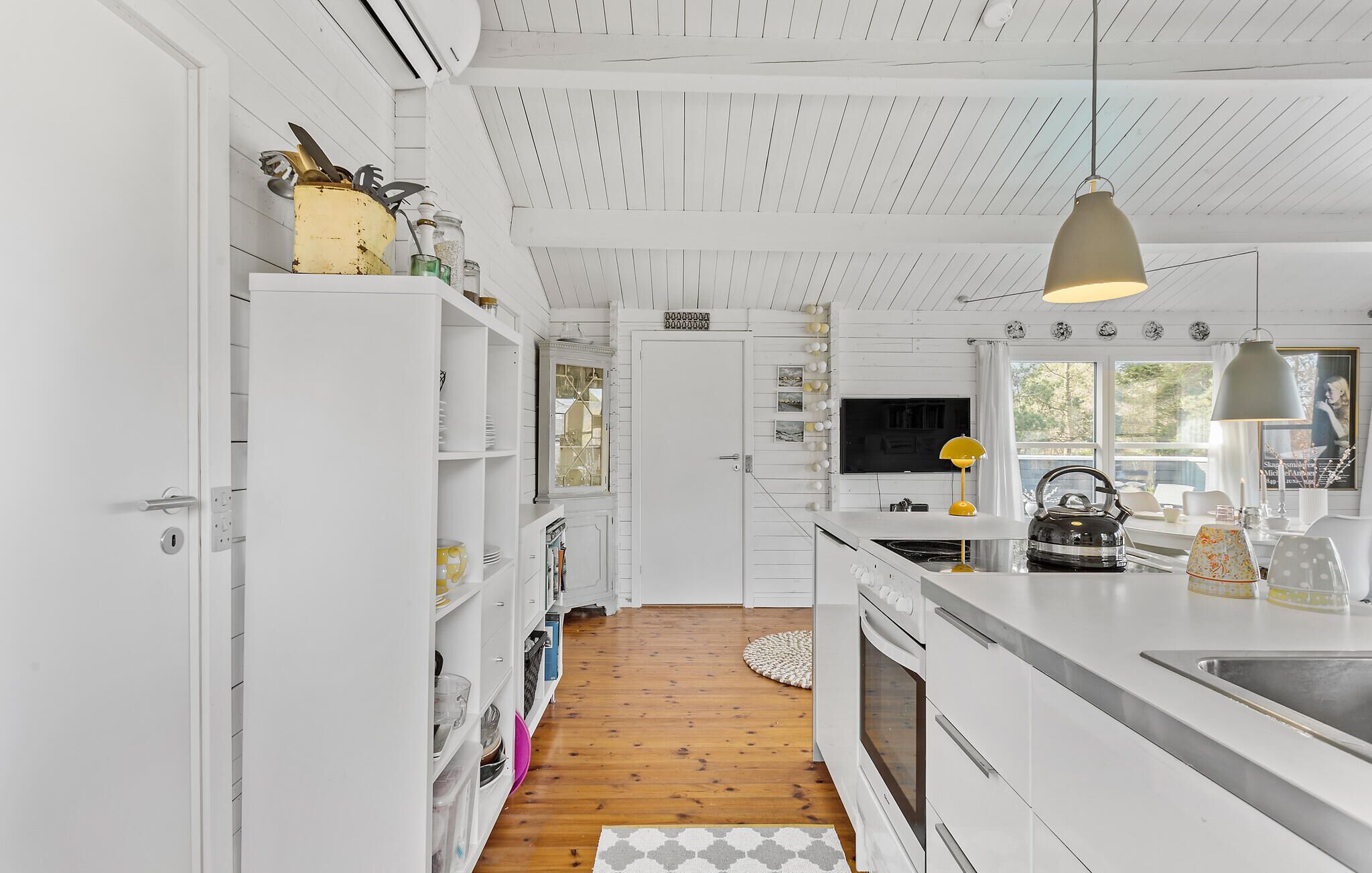 Een moderne keuken met witte kasten, een houten vloer en een groot eiland met een spoelbak.