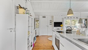 Ett modernt kök med vita skåp, ett trägolv och en stor köksö med en diskho.