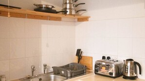 A kitchen with a sink, stove, toaster, kettle, and hanging pots. - Lovely 1 bed Apt - Buckinghamshire (High Wycombe)