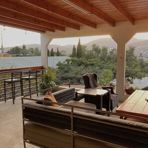 An outdoor seating area with a view of a lake and mountains.