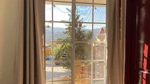 Ein Fenster mit Blick auf eine Terrasse, einschließlich Blumentöpfen und Gartenmöbeln.