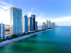 A coastal cityscape with high-rise buildings along a beach.