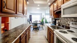 Una cocina moderna con armarios de madera, encimera de granito, comedor con sillas y una estufa blanca.