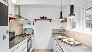 Una cocina moderna con estufa a gas, horno y ventana que deja entrar luz natural.