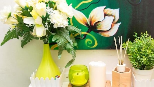 Una mesa con un jarrón de flores, una vela y un candelabro verde.