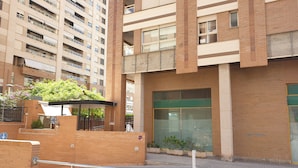 A multi-story building with a brick facade, large windows, and a gated entrance. - Oceanografico Apartments (Valencia)