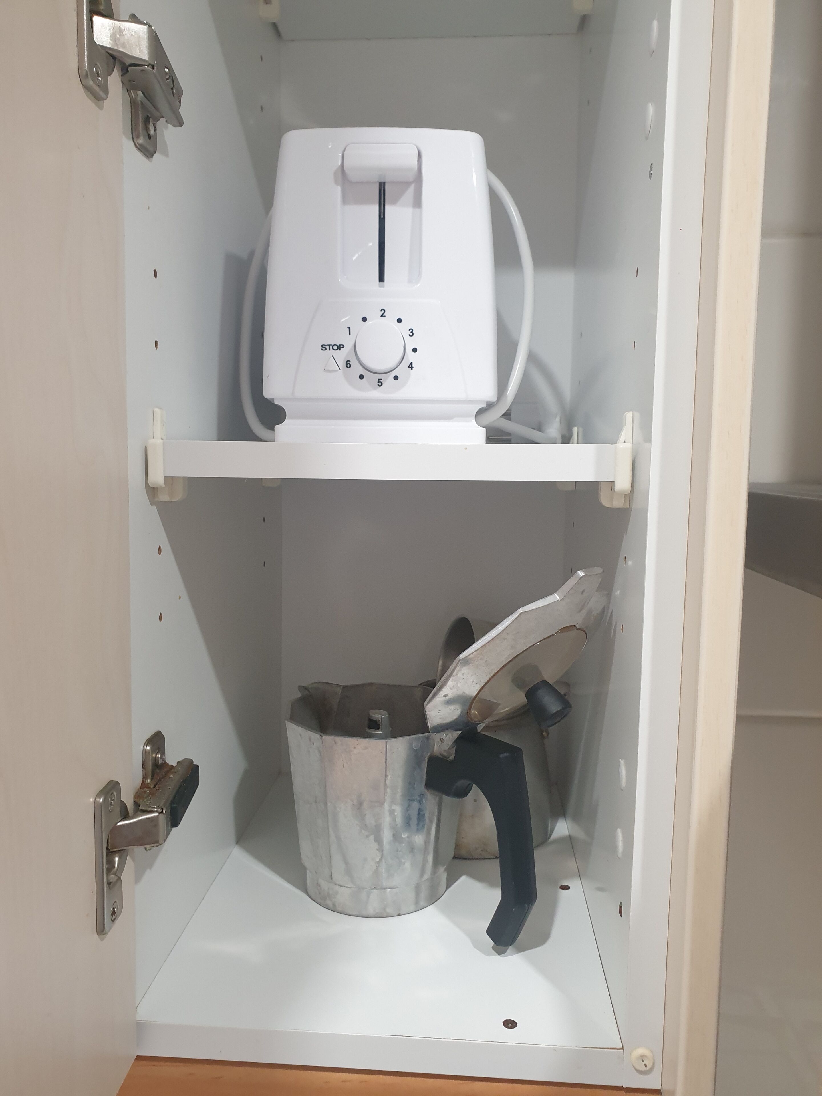 A white utility cabinet with a white electrical device on top and a metal bucket below.