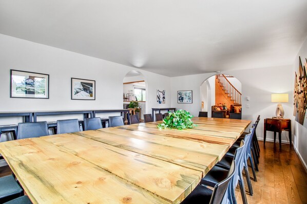 A spacious dining area with a long wooden table, multiple chairs, and a staircase leading to an upper level. - Ski Lodge: Ski Rental near Monarch Mountain. Ideal for large groups, bachelor parties, corporate retreats (Salida)