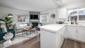 A modern kitchen with white cabinets, a large island, and a dining area with a sofa and coffee table. - Luxurious Retreat/Hot Tub/Mountain View/4 Beds (Bighorn No. 8)