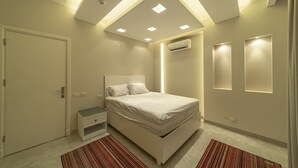 Une chambre à coucher moderne, équipée d’un lit, d’une table de chevet et d’un système de climatisation intégré.