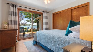 Un dormitorio con cama, mesita de noche, escritorio y vistas al exterior.