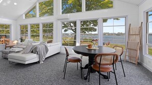 Una habitación amplia con una gran mesa de comedor, asientos cómodos y ventanas grandes que ofrecen vistas al exterior.