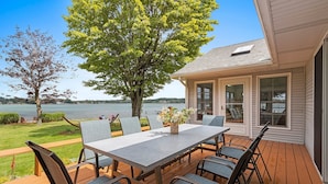 Una terraza con mesa y sillas, con vista a un lago.