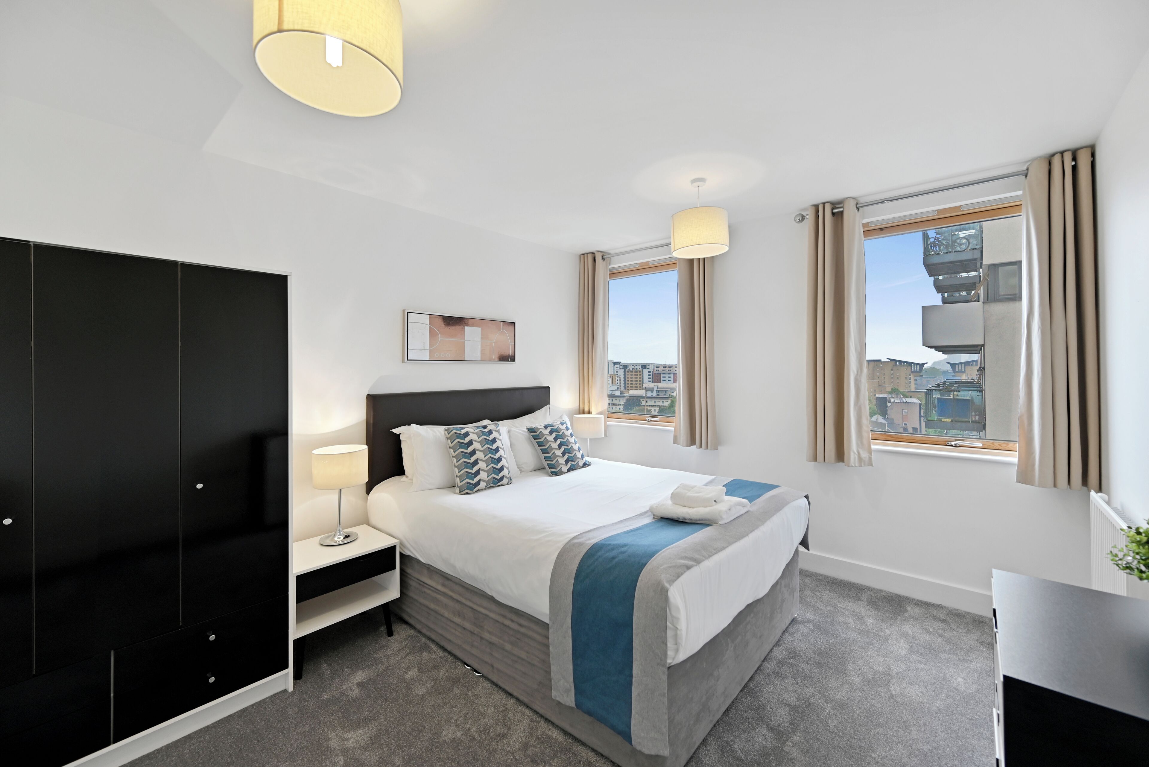 Habitación de hotel moderna con una cama grande, un armario, un escritorio y vistas a la ciudad.