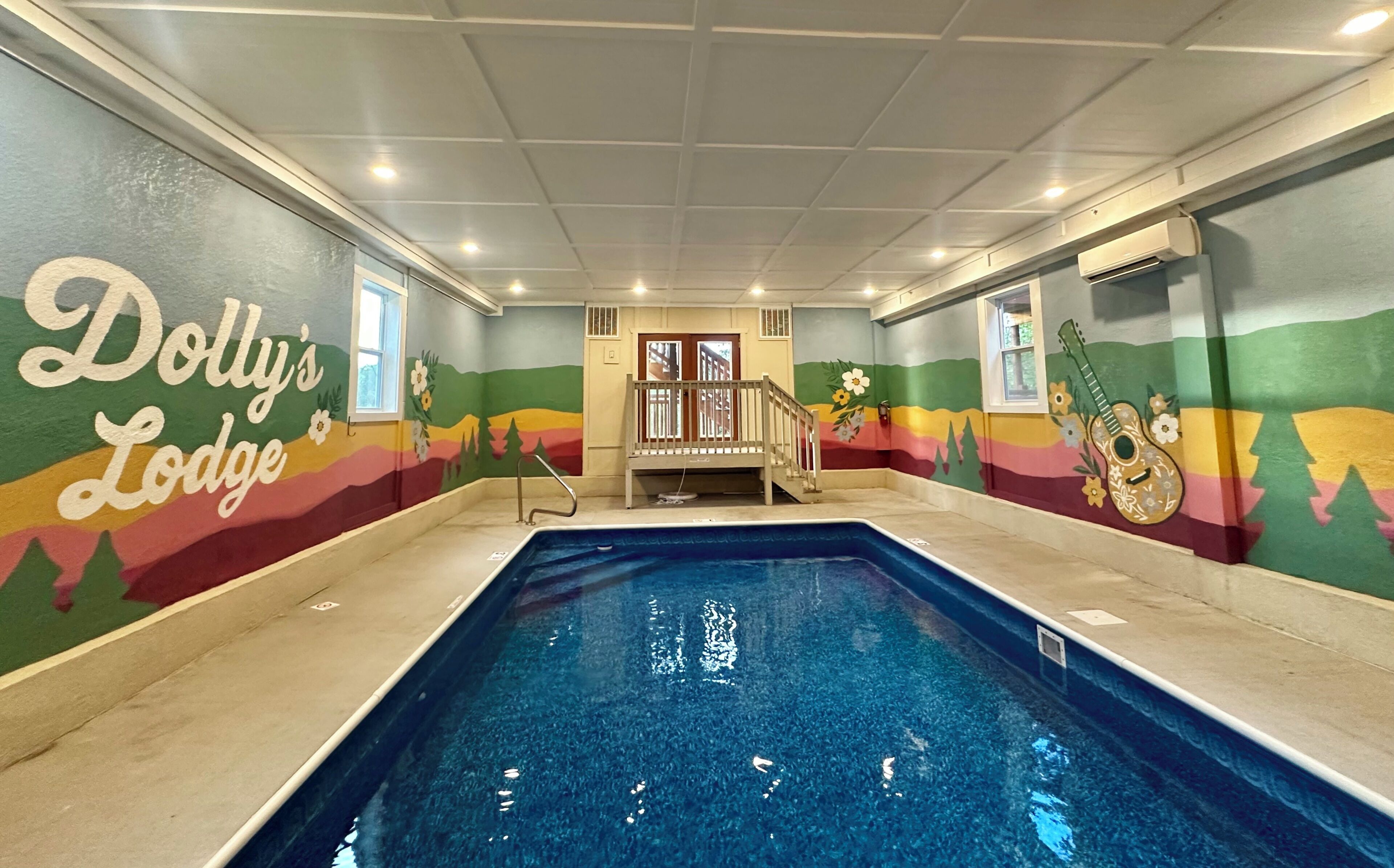 Una piscina interior con un mural colorido en las paredes y una zona de terraza de madera.