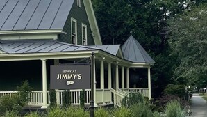 A two-story building with a porch, a sign reading "STAY AT JIMMY'S", and a pathway leading to it. - Stay At Jimmy's (Woodstock)