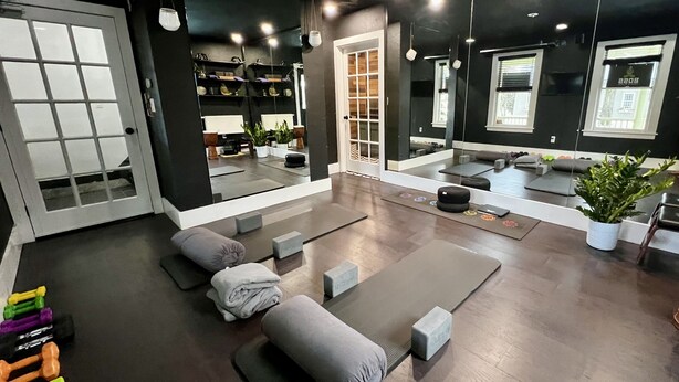 A modern fitness center with exercise equipment, mirrors, and a reception area. - Stay At Jimmy's (Woodstock)