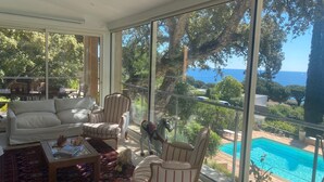 Un salón amplio con ventanas grandes, una piscina y mobiliario de exterior.