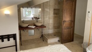 Un baño con tocador de madera, dos lavabos, un espejo y zona de ducha.
