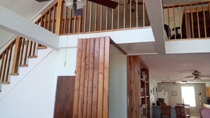 A multi-level home with a wooden staircase, a ceiling fan, and a kitchen area with wooden cabinets and chairs. - Forest Get Away! Surrounded by National Forest. Beautiful home in the woods.  (Mena)