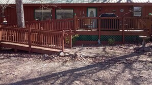 A cabin with a covered porch, a wooden deck, and a fenced outdoor area. - Forest Get Away! Surrounded by National Forest. Beautiful home in the woods.  (Mena)