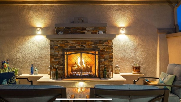 An outdoor patio with a stone fireplace, two chairs, and a table. - 🌵 Anthem Country Club Retreat.  Heated Saltwater Pool, Spa, Casita & Office. (New River)