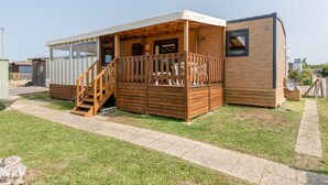 Une maison mobile en bois dotée d’un porche couvert et d’une petite terrasse.